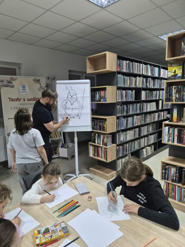 Maciej Kisiel - rysownik, twórca komiksu, rysuje postać na flipcharcie, wokół uczestnicy warsztatów